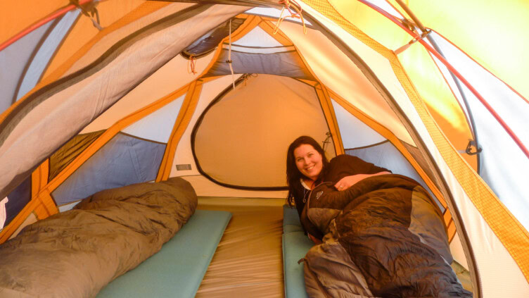 A woman in a tent using a sleeping bag.