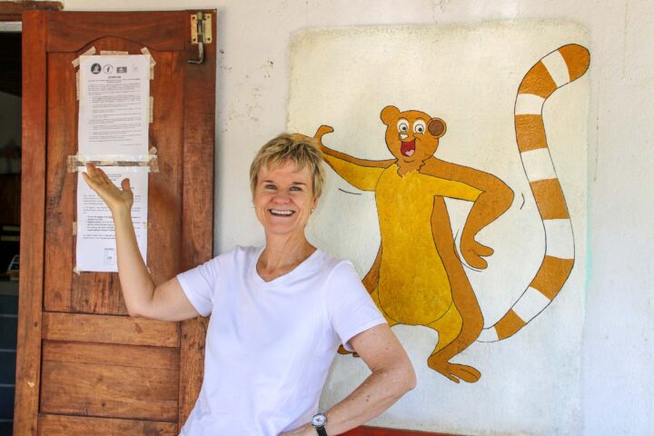 A woman smiling alongside a mural.