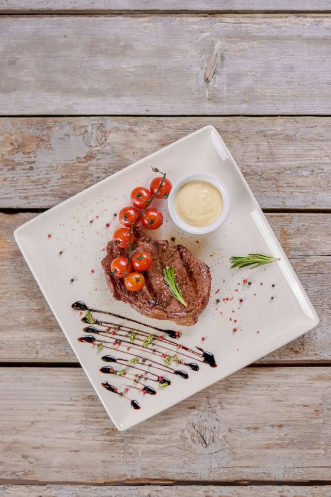 Steak and tomato dinner on wood table.
