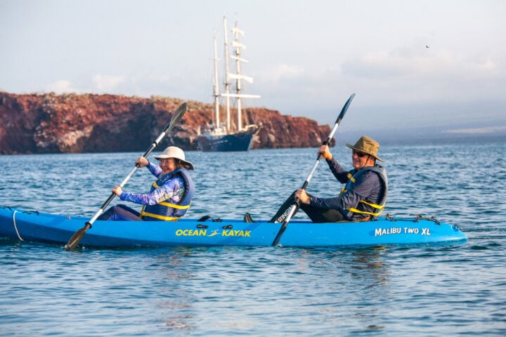 two smiling tourists kayaking in the galapagos