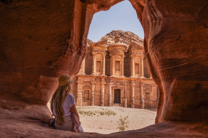 Rear view of blonde tourist woman in hidden viewpoint The Monastery, ancient city of Petra. Historical and archaeological city in southern Jordan.